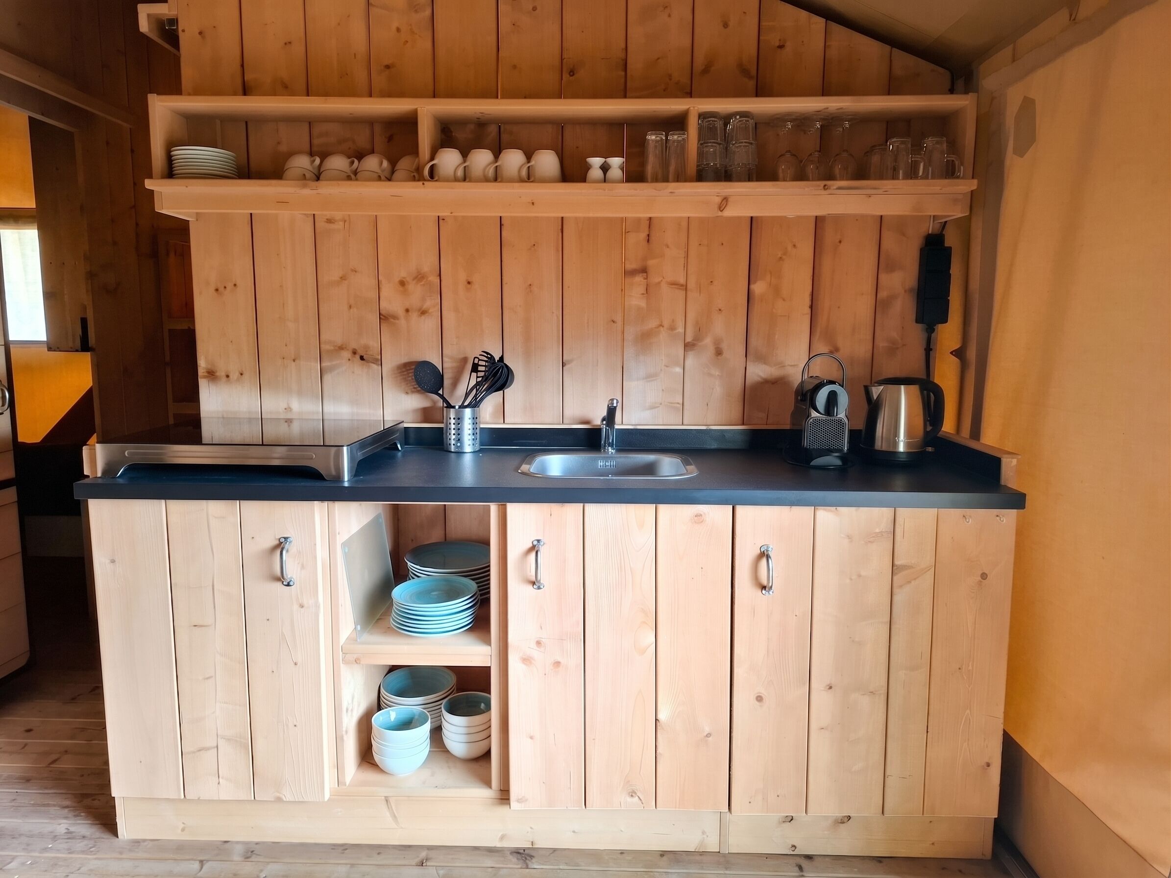 Una cocina de madera con un lavabo, estantes y armarios.