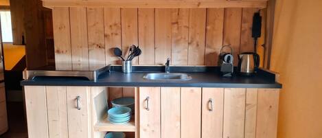 Una cocina de madera con un lavabo, estantes y armarios.