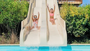 Two children sliding down a water slide into a pool surrounded by greenery. - RCN Camping La ferme du Latois (Coëx)