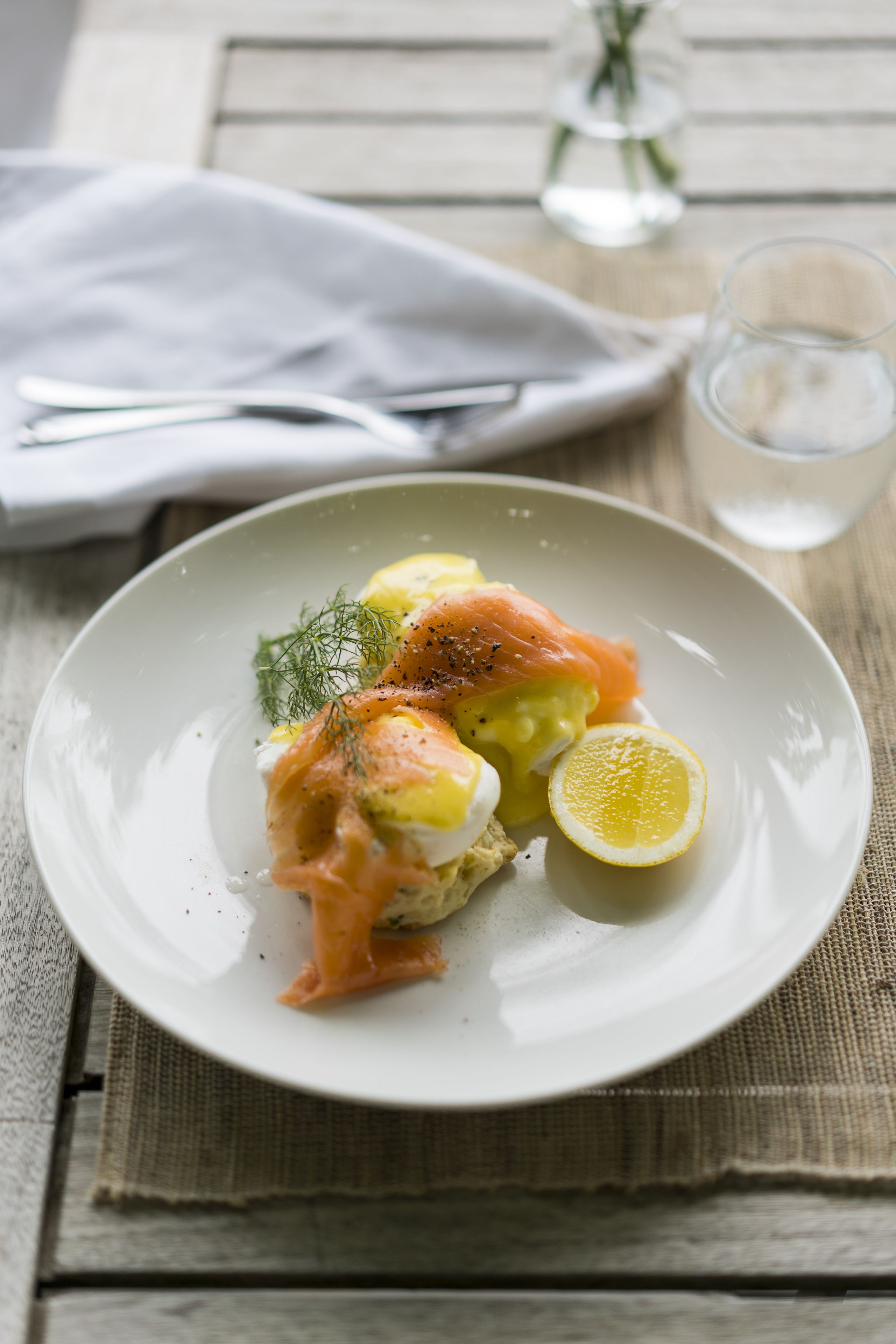 A plate of food with salmon, eggs, and a lemon wedge on a white plate.