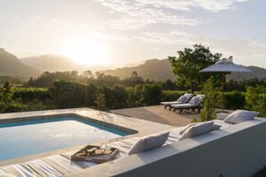 A poolside area with a wooden deck, lounge chairs, and a table with drinks and snacks. - Cape Vue Country House (Franschhoek)