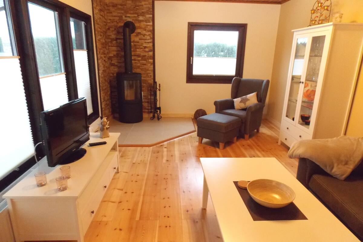A cozy living room with a fireplace, a comfortable sofa, a television, and a dining area with a table and chairs.