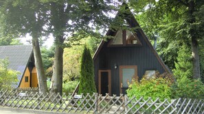 A wooden cabin with a sloped roof, surrounded by trees and a wooden fence. - Waldsee Feriendienst (Clausthal-Zellerfeld)