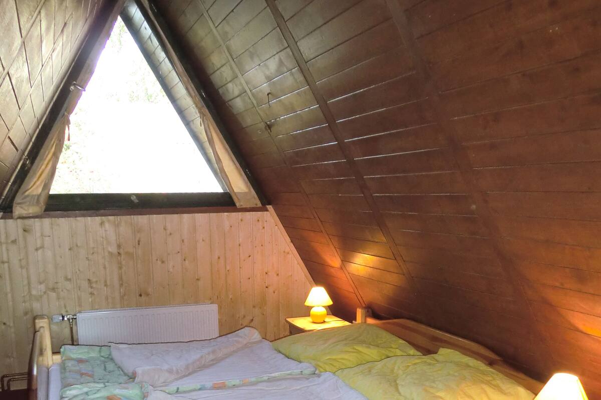 A wooden bed in a sloped ceiling room with two bedside lamps.