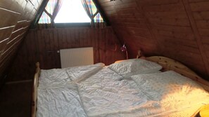 A single bed in a wooden room with a sloped ceiling and a window with curtains. - Waldsee Feriendienst (Clausthal-Zellerfeld)