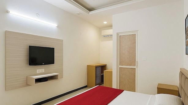 A modern hotel room with a bed, a TV mounted on the wall, a wardrobe, and a door.