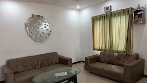 A living room with two brown leather sofas, a glass coffee table, and a wall-mounted decorative mirror.