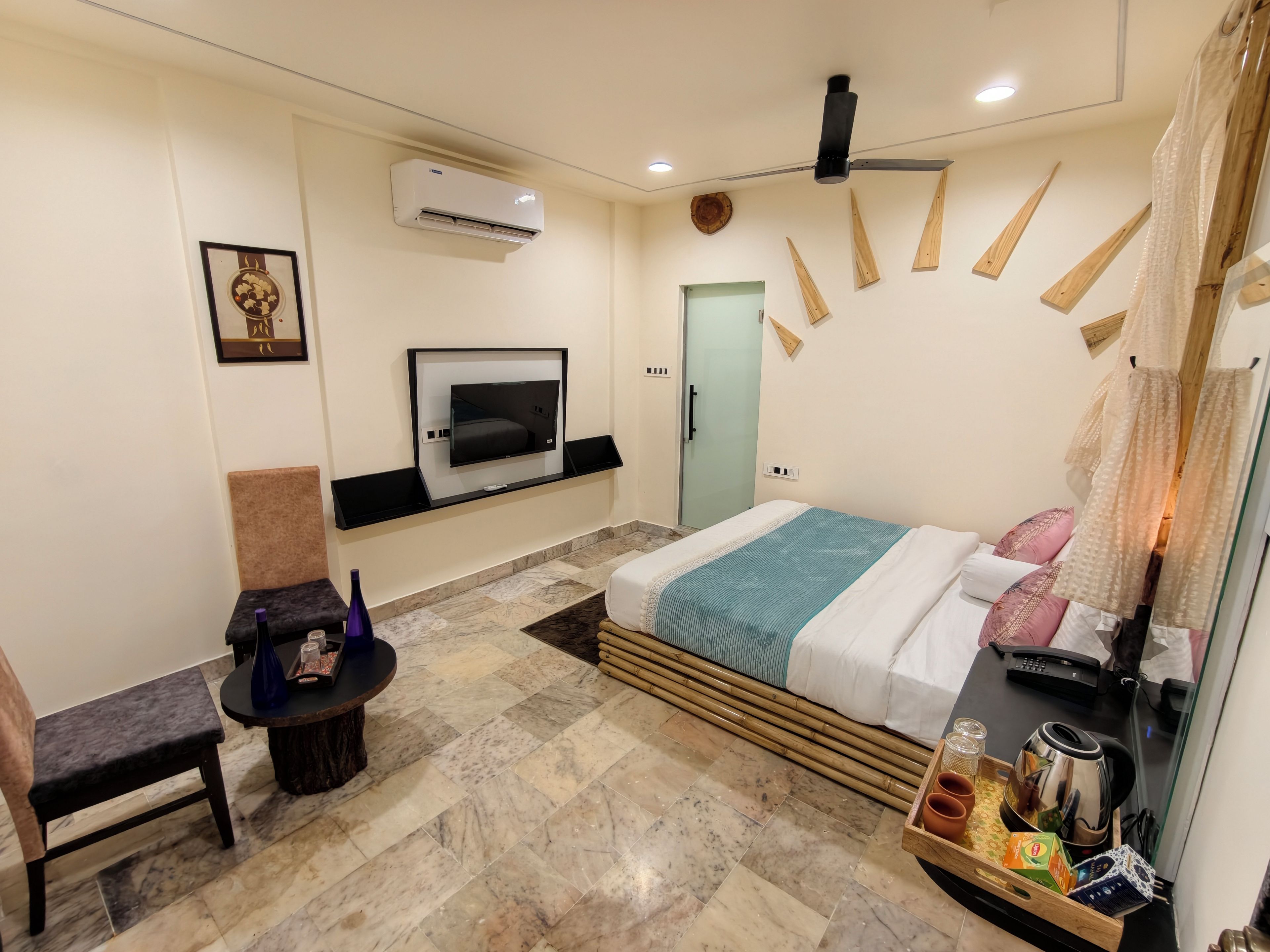 Une chambre d’hôtel avec un lit, un téléviseur fixé au mur, une chaise, une petite table et un plateau avec divers objets.