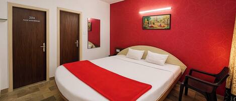 Une chambre d’hôtel avec un grand lit, un mur d’accent de couleur rouge et un plancher en bois.