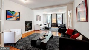 A modern living room with a fireplace, white and black sofas, a coffee table, and artwork on the walls. - BlancNoir Bed & Breakfast (Baltimore)
