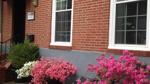 A red brick building with two white-framed windows and a small sign above the door. - BlancNoir Bed & Breakfast (Baltimore)