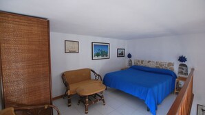 A bedroom with a bed, wicker furniture, and framed pictures on the wall. - Loft Lipari (Lipari)