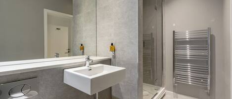 A modern bathroom with a large mirror, a sink, and a glass shower enclosure.