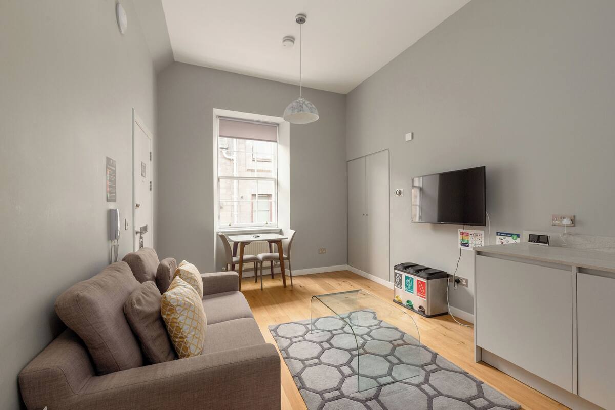 A modern living room with a sofa, a dining table, and a TV.