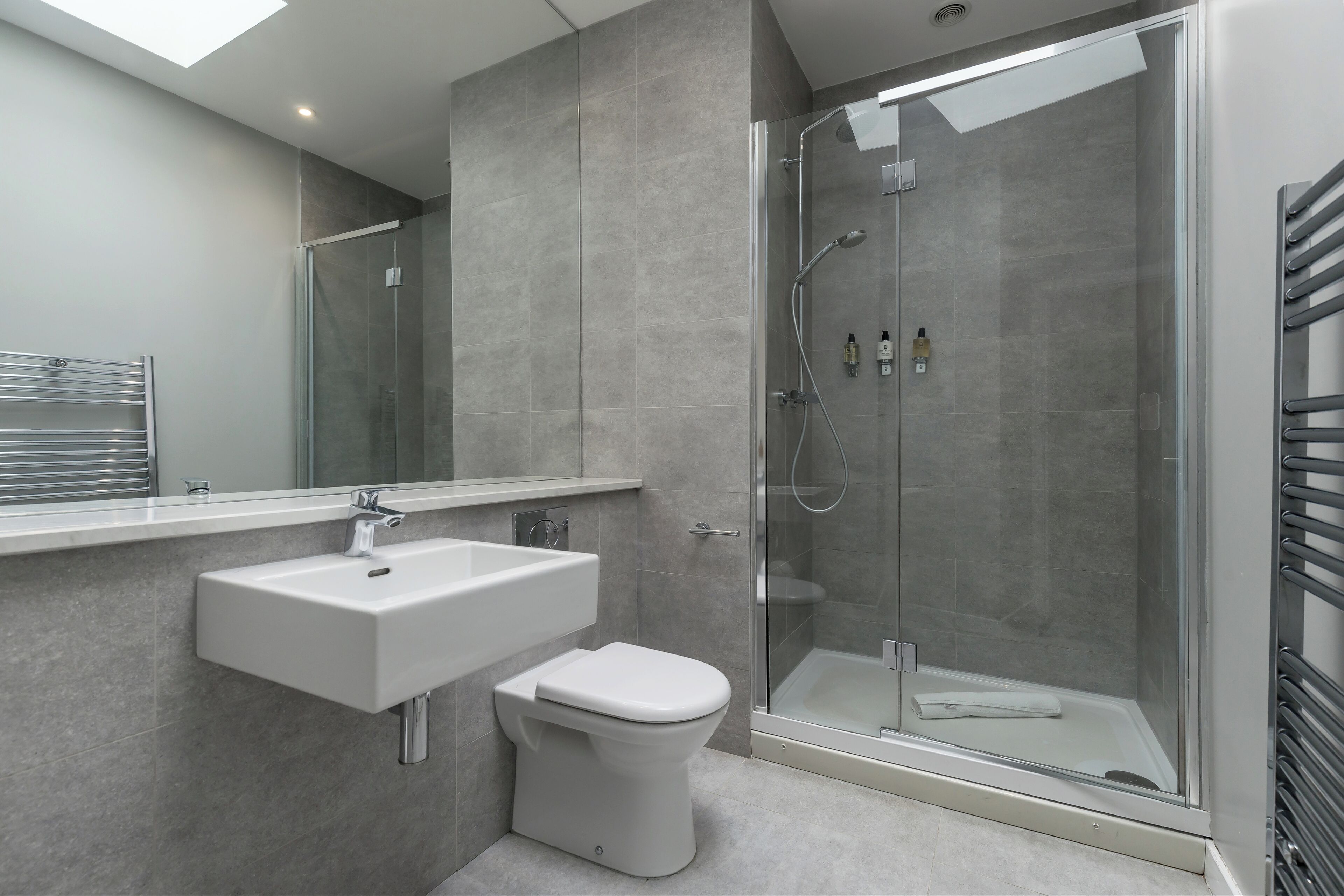 Une salle de bain moderne avec une douche à parois de verre, un lavabo blanc et des toilettes.