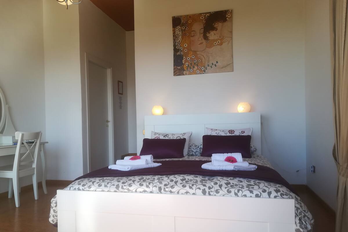 Un dormitori ordenat amb un llit, làmpades de sobretaula i un quadre a la paret.