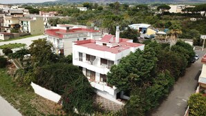 A modern two-story house with a red roof, surrounded by lush greenery and a mountain in the background. - Il Giardino di Villa Anna (Trecase)