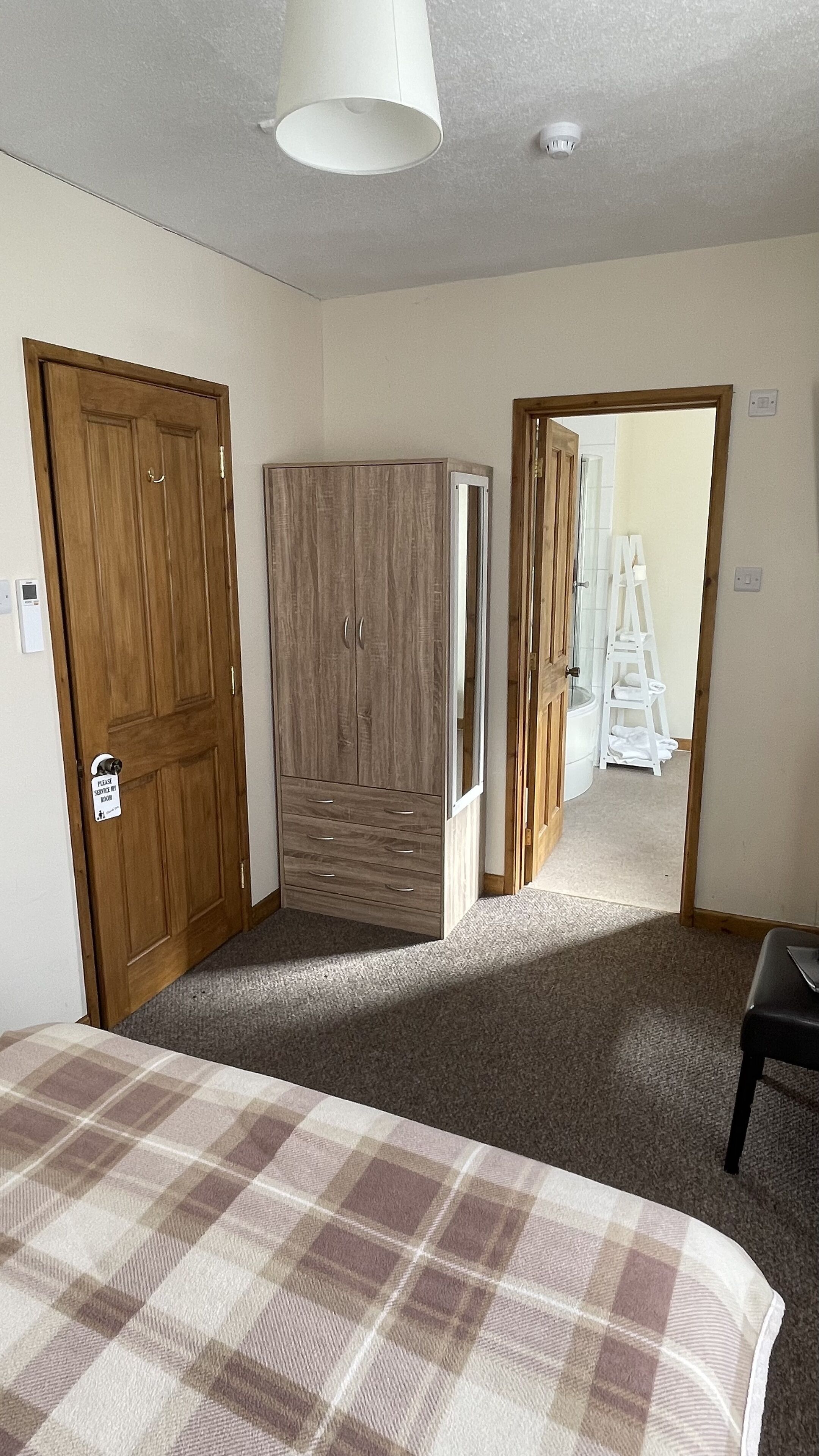 Un dormitorio con cama, armario, espejo y puerta que da a otra habitación.