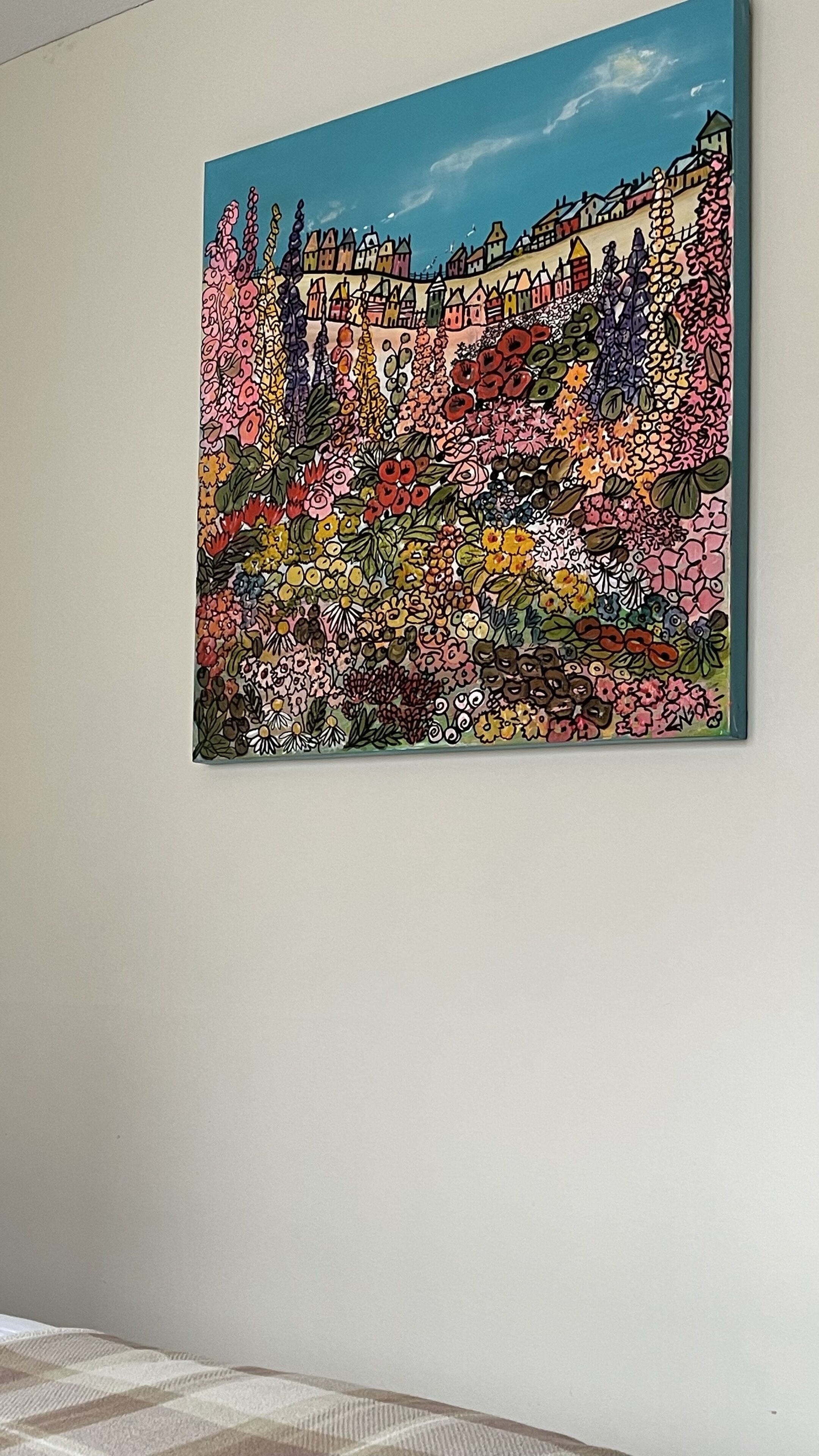 A colorful painting of a town with houses and flowers on a wall.