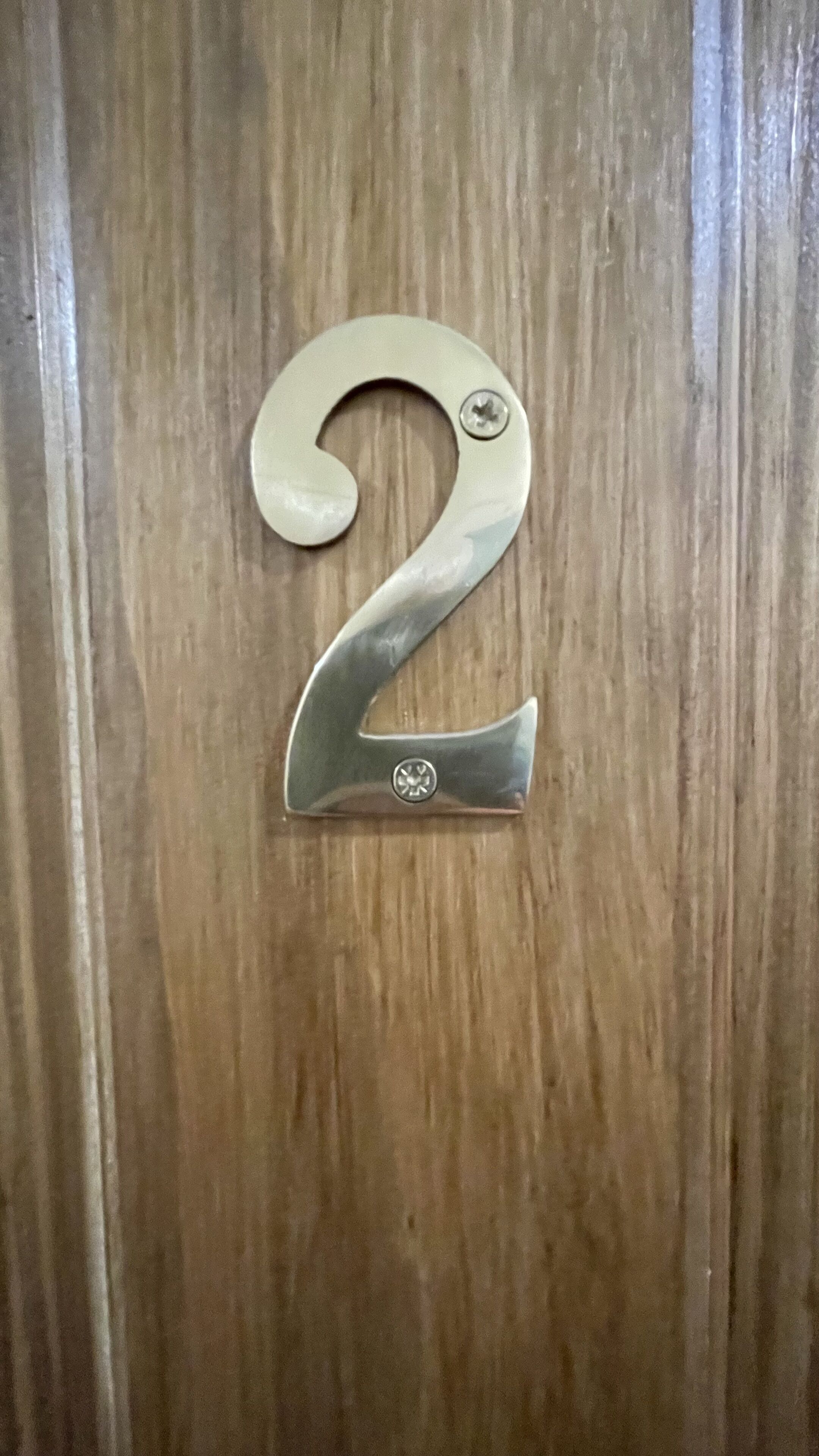 A metallic number '2' plaque on a wooden door.