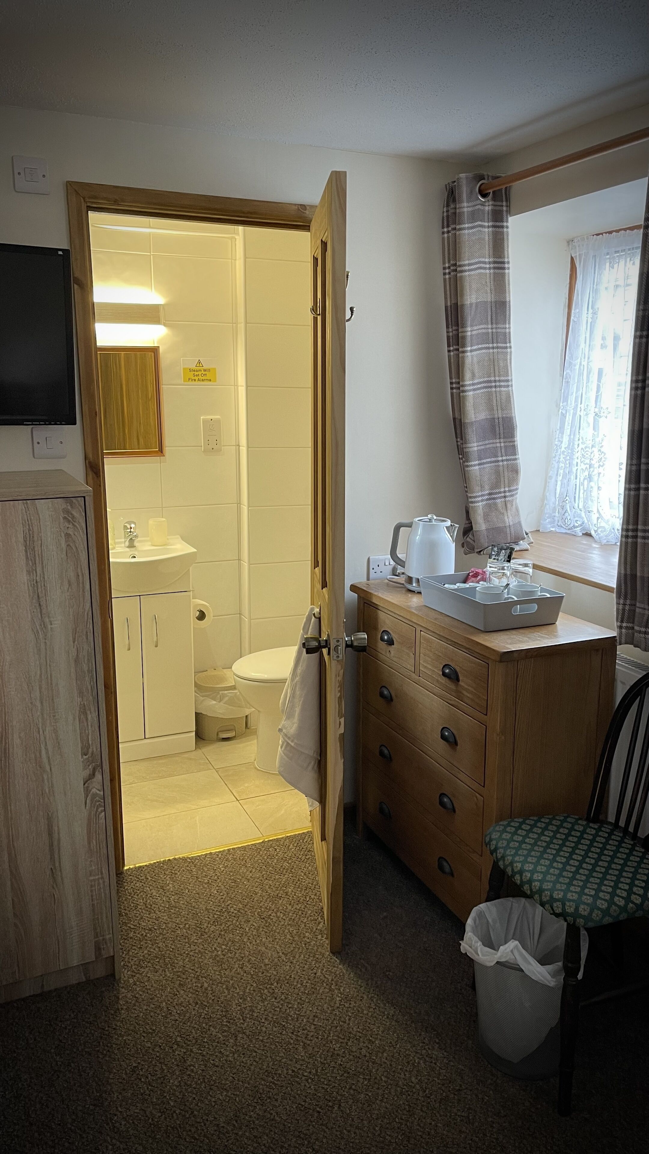 Ein Badezimmer mit Dusche, Toilette, Waschbecken und einem Schminktisch mit Schubladen und Spiegel.