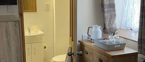 Ein Badezimmer mit Dusche, Toilette, Waschbecken und einem Schminktisch mit Schubladen und Spiegel.