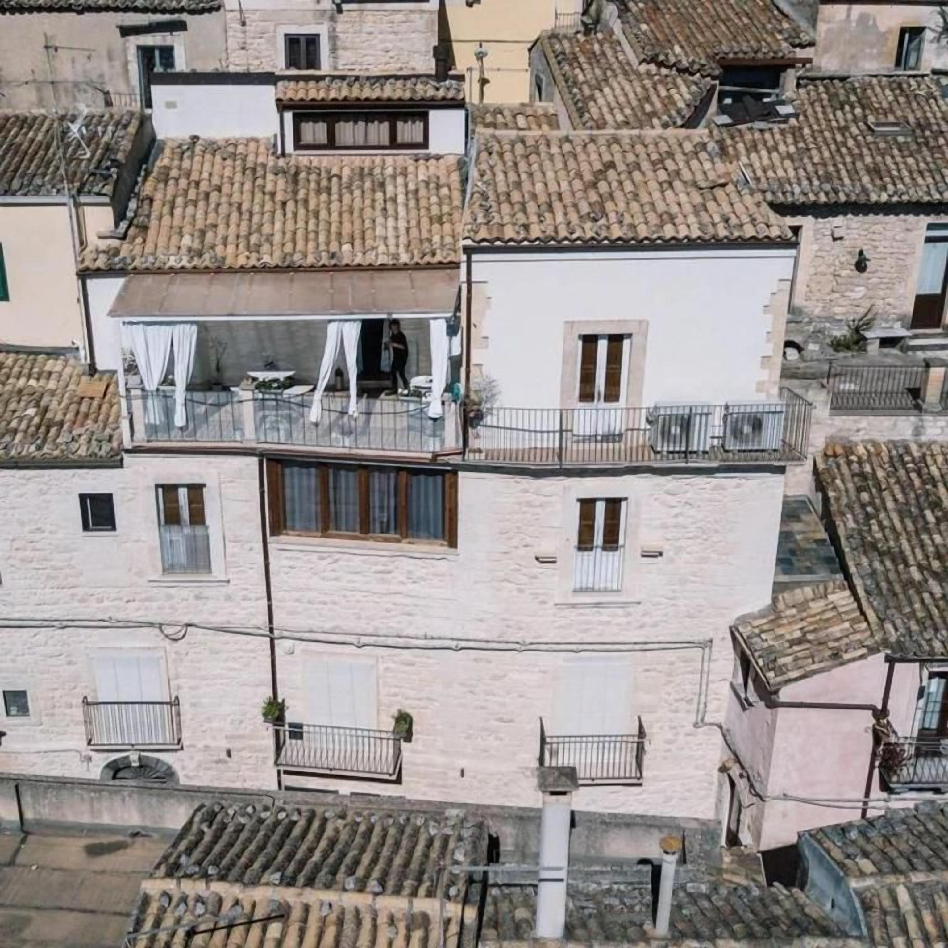 Un immeuble à plusieurs étages doté de balcons, d’une terrasse et d’un toit traditionnel recouvert de tuiles.