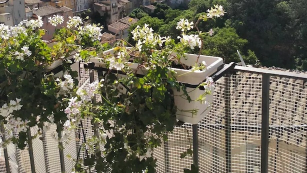 A view of a hillside town with buildings and a prominent structure on top. - La Casa di Matilde (Ragusa)