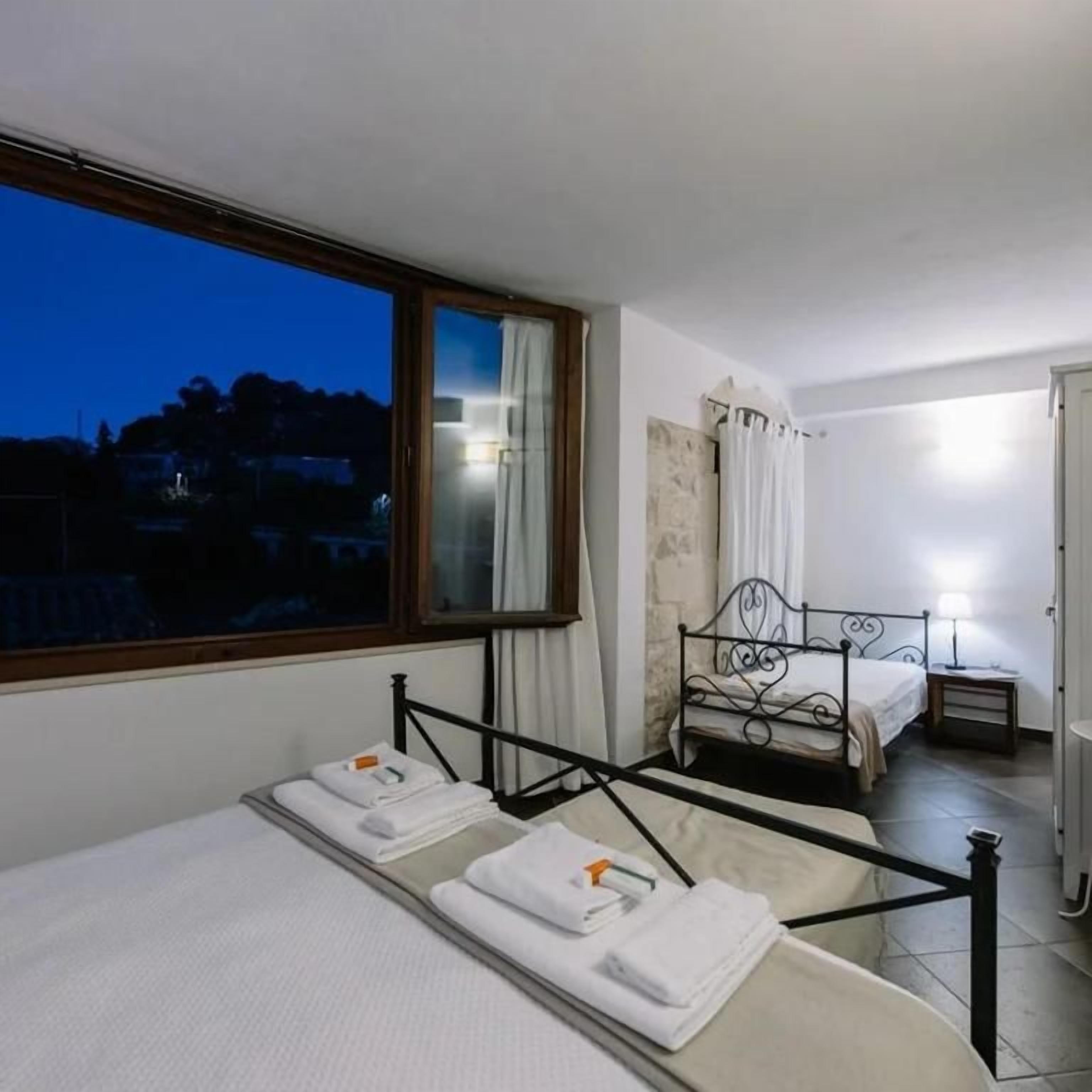 Une chambre d’hôtel avec un lit, un petit lit, une fenêtre, une table de chevet et une salle de bain.