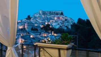 Un balcon offrant une vue sur une ville perchée sur une colline, avec ses maisons serrées les unes contre les autres, au crépuscule.