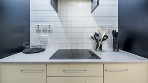 A kitchen with a black stovetop, white tiled backsplash, and a set of knives on the counter. - Deluxe Kensington Apartment With Balcony (London)