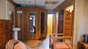 A room with a wooden cabinet, a white sink, wicker chairs, and a small table. - Hotel North Resort (Paramaribo)