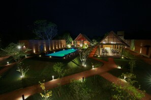 A nighttime view of a resort with a swimming pool, outdoor dining area, and well-lit pathways. - Roo Mansala Boutique Villas (Sigiriya)