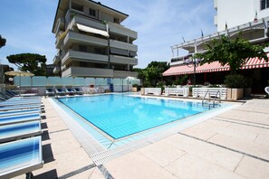 Una piscina al aire libre de temporada, sombrillas, tumbonas