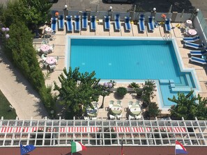 Piscine extérieure en saison, parasols, chaises longues