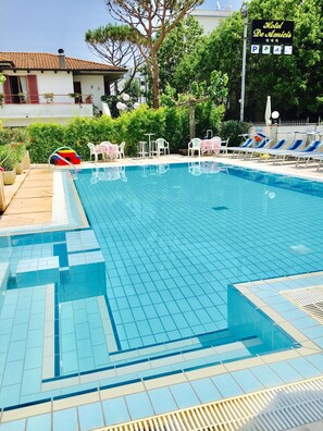 Una piscina al aire libre de temporada, sombrillas, tumbonas