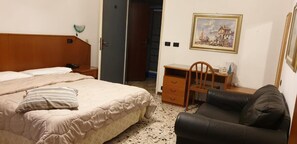 A bedroom with a bed, a desk, a chair, and a door leading to a bathroom. - Albergo Ristorante Roma (Legnano)