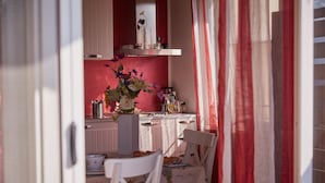 A kitchen with a dining area, featuring a table with a floral tablecloth, chairs, and a vase with flowers. - Cento Passi Dal Duomo (Arezzo)