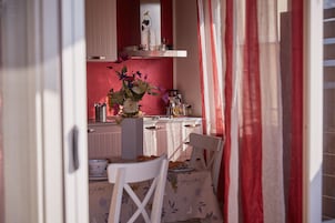 Una cocina con comedor, que incluye una mesa con mantel floral, sillas y un florero con flores.