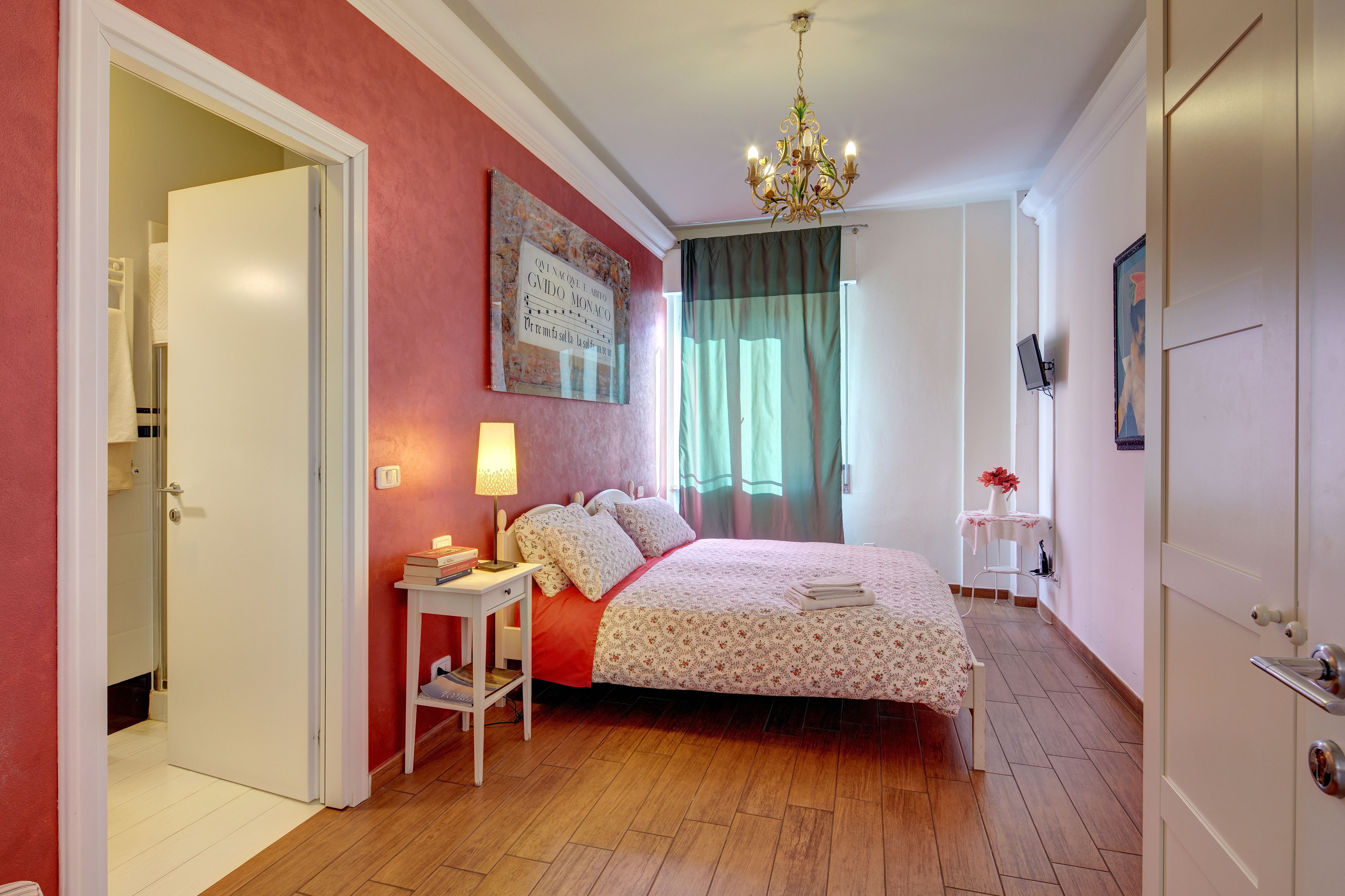 Un dormitorio con cama, mesita de noche, lámpara y un cuadro en la pared.