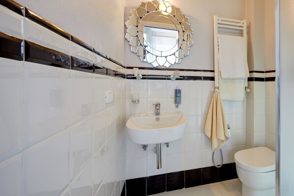 A modern bathroom with a white sink, mirror, and toilet. - Cento Passi Dal Duomo (Arezzo)