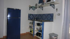 A compact kitchen with a blue refrigerator, a microwave, and a sink. - Ambra (Lipari)