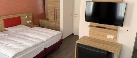 A hotel room with two beds, a TV, a desk, and a wardrobe.