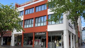 Een modern gebouw met een winkel op de begane grond en appartementen op de bovenverdiepingen.