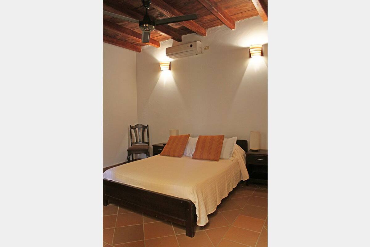 A bedroom with a wooden bed, two nightstands, a chair, and a ceiling fan.