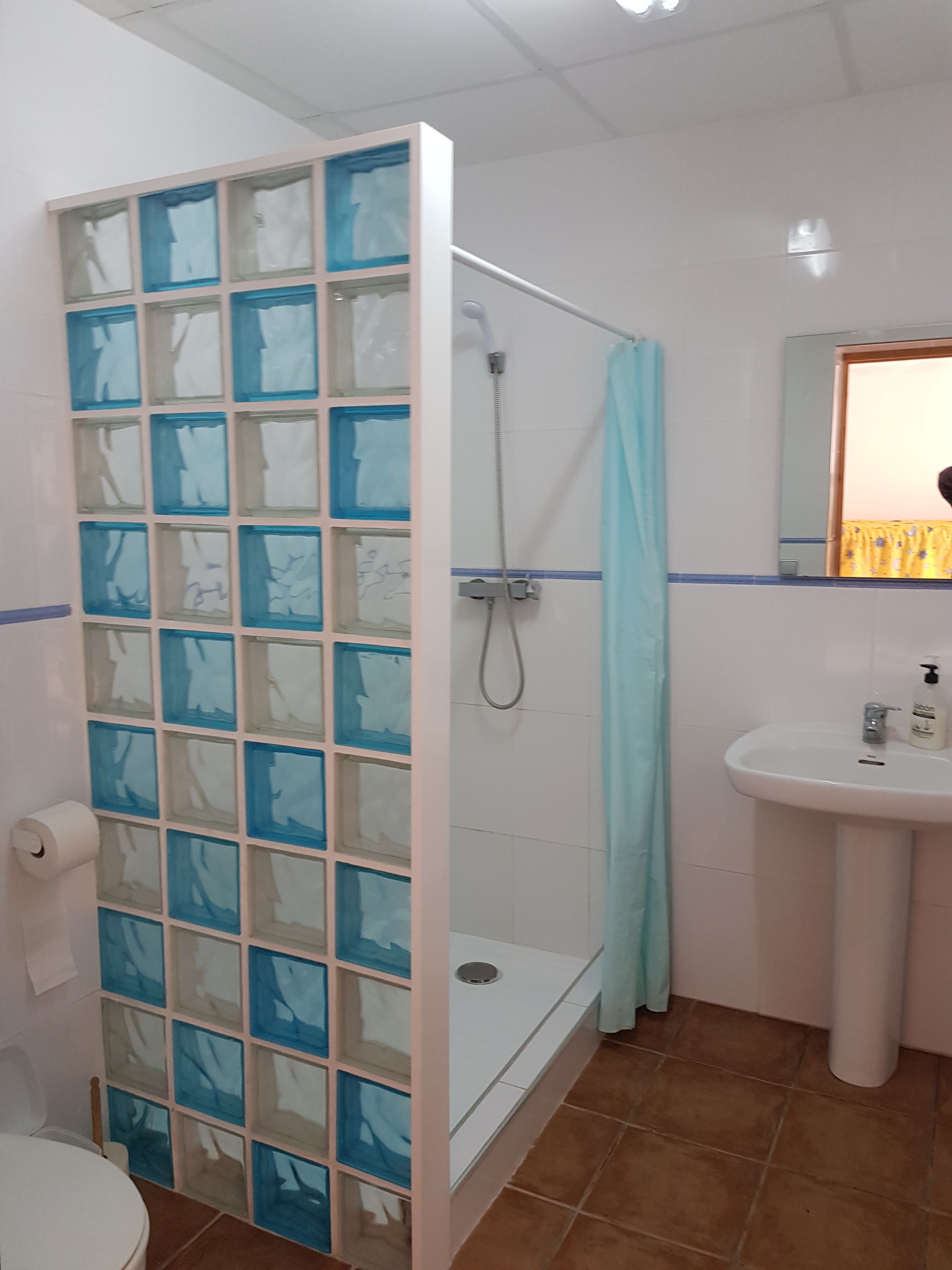 Une salle de bain avec une douche à parois en verre, un lavabo et des toilettes.