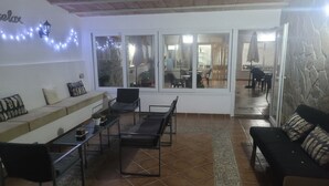 A cozy living room with a sofa, chairs, and a coffee table. Large windows offer a view of the outdoor area. - La Llar de Laura (Amposta)