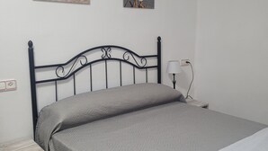 A bedroom with a bed, a nightstand, a lamp, and two wall-mounted pictures. - La Llar de Laura (Amposta)