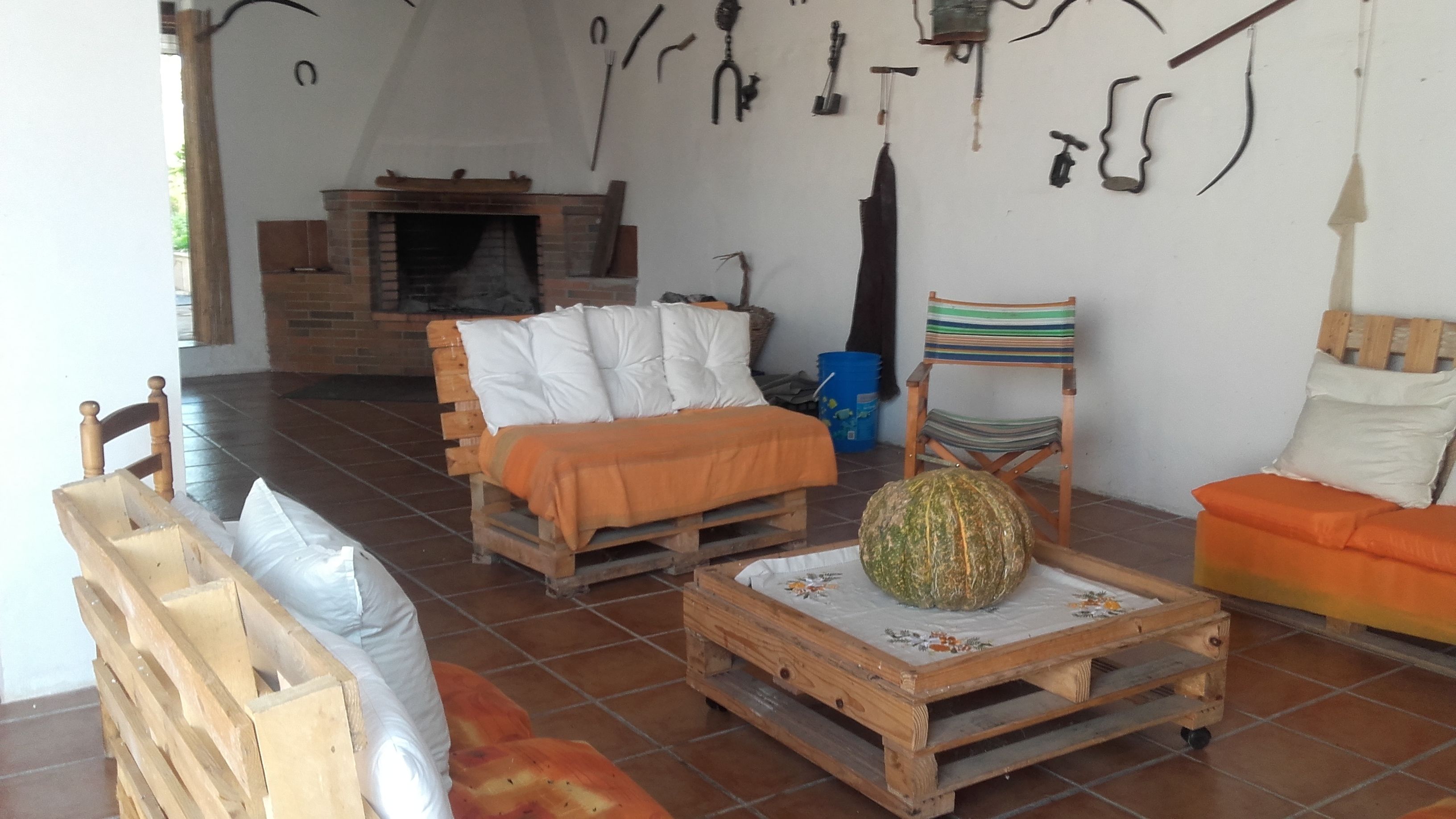 Un salón rústico con chimenea, muebles de madera y varias herramientas colgadas en la pared.
