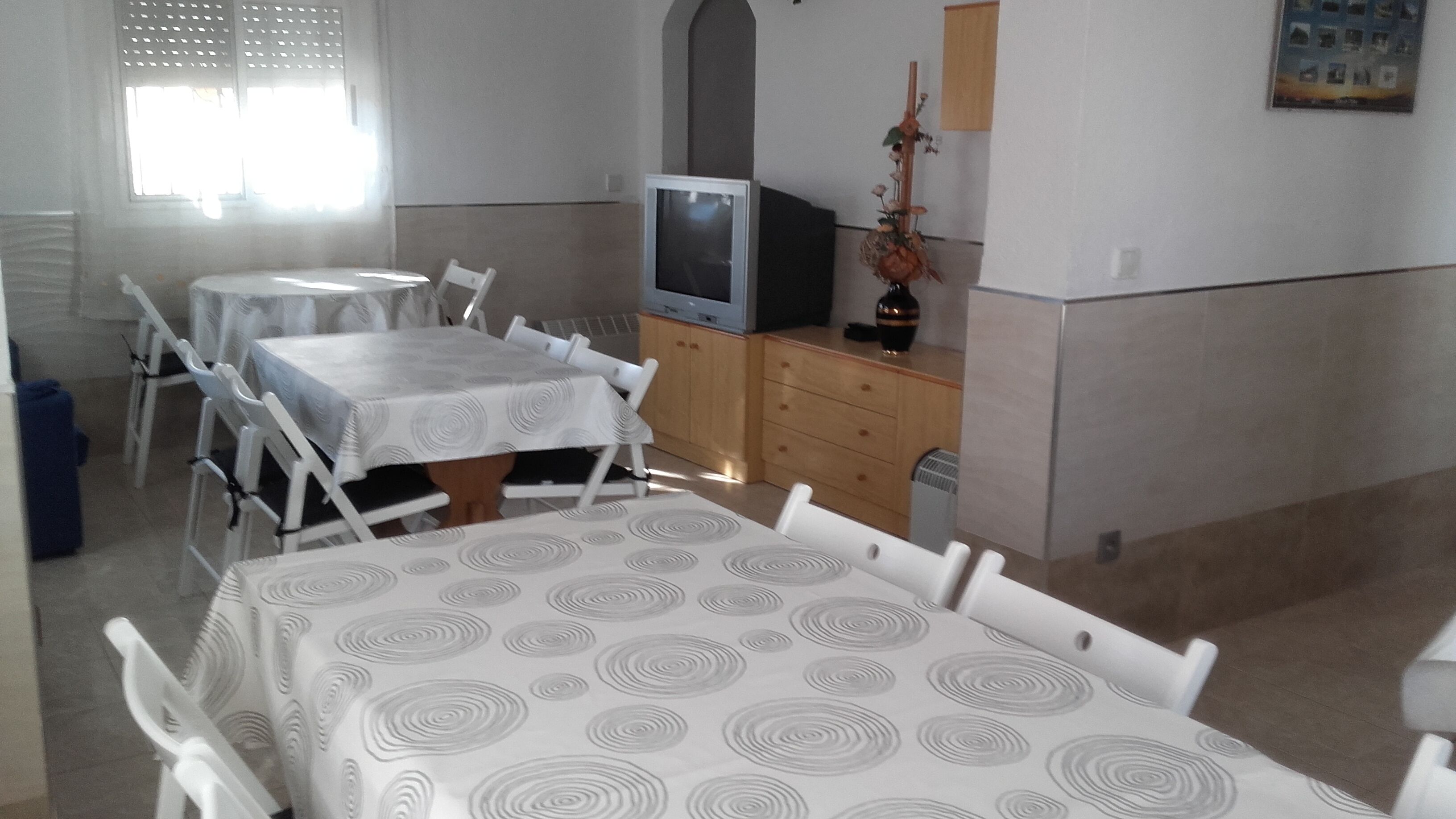 Una habitación pequeña y limpia, con una cama, televisión, cómoda y ventana.